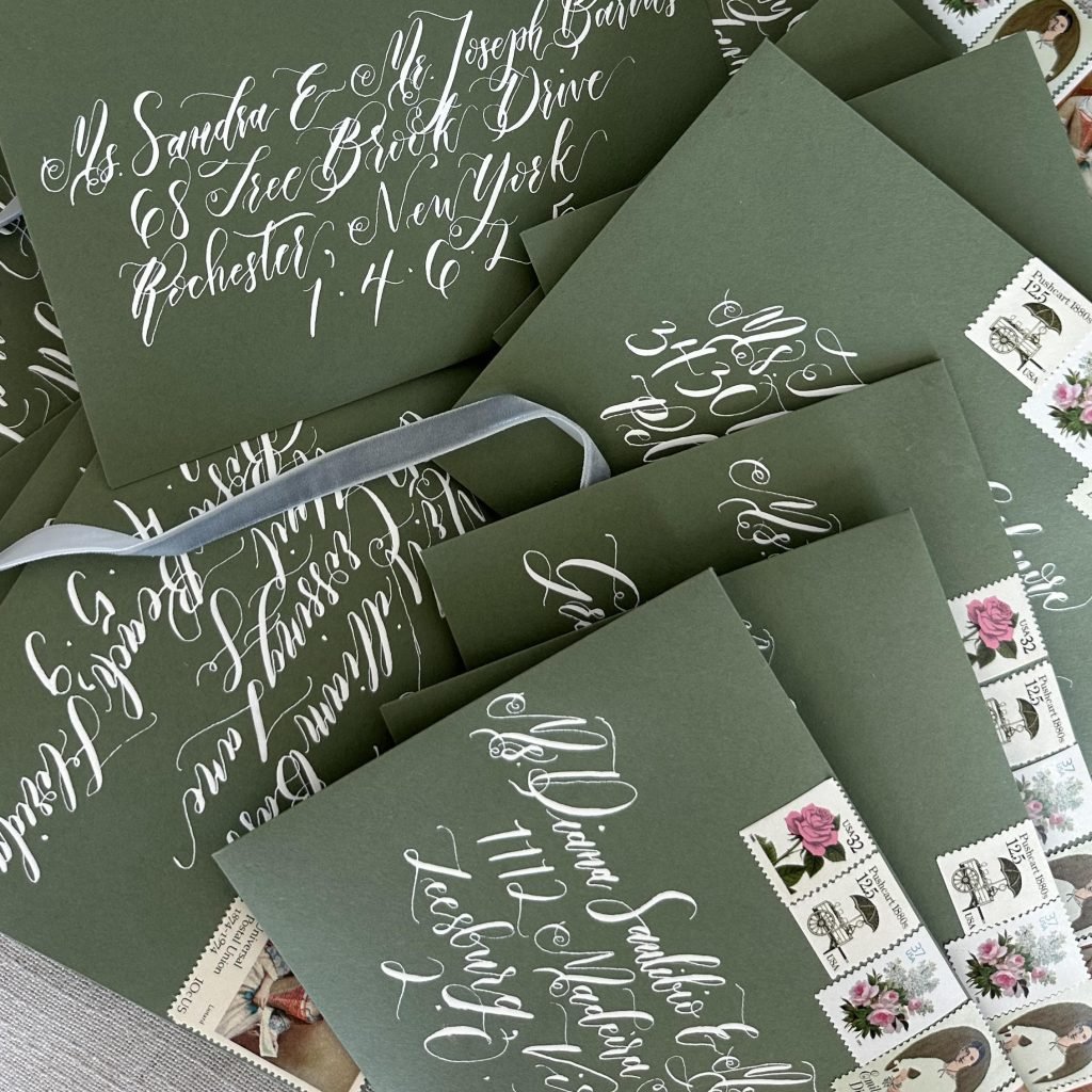 Stack of green envelopes with white ink calligraphy in a modern style