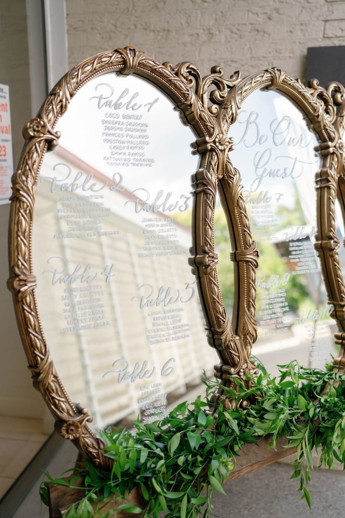 wedding seating chart on large bronze mirror done in white ink calligraphy